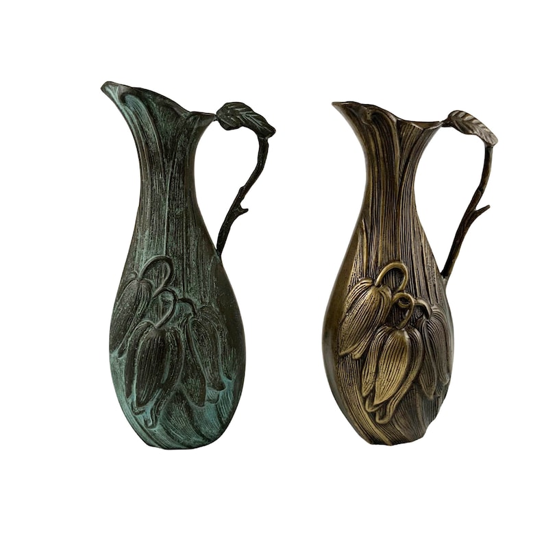 Pu&ograve; includere: Due brocche decorative in bronzo con un motivo floreale. Una brocca &egrave; di colore blu verdastro e l'altra &egrave; di colore bronzo dorato.