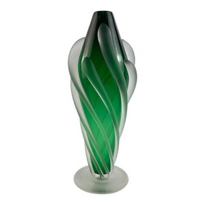 May include: A tall, elegant glass vase with a swirling design. The vase features a vibrant green interior and clear, frosted glass exterior elements. The base is a circular, frosted glass. The overall shape is elongated and artistic.