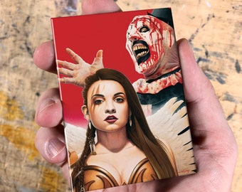 May include: A red background with a woman with long brown hair wearing a gold and brown costume and a white feathered halo. She is looking at the viewer. Behind her is a man with a white and red clown costume with a bloody face. He is looking to the left. The text "Volfy" is in the bottom right corner.