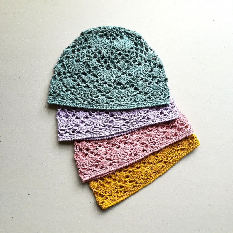 May include: Four crocheted hats stacked on top of each other. The top hat is teal, the second is lavender, the third is pink, and the bottom hat is yellow.