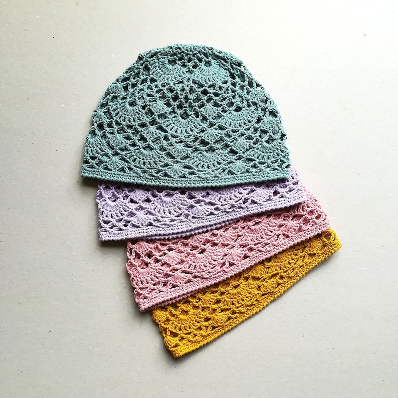 May include: Four crocheted hats stacked on top of each other. The top hat is teal, the second is lavender, the third is pink, and the bottom hat is yellow.