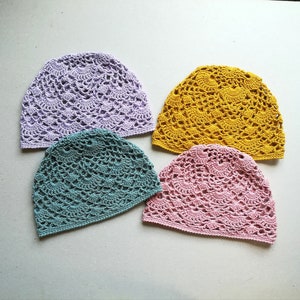 May include: Four crocheted hats in different colors: lavender, teal, pink, and yellow. The hats are made with a delicate openwork stitch.