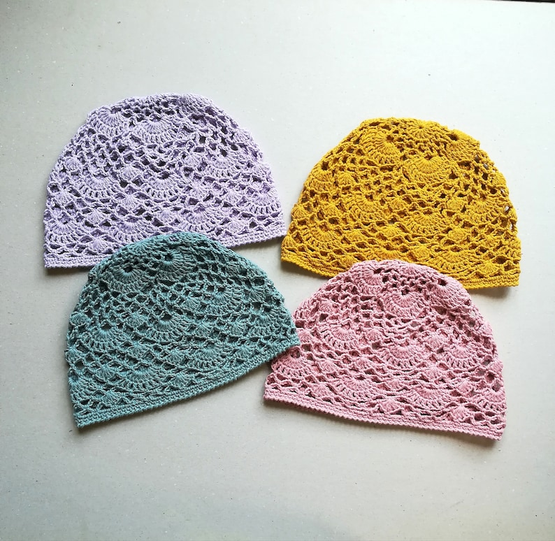 May include: Four crocheted hats in different colors: lavender, teal, pink, and yellow. The hats are made with a delicate openwork stitch.