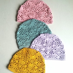 May include: Four crocheted hats in different colors: pink, teal, lavender, and yellow. The hats are stacked on top of each other.