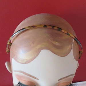 May include: A tortoiseshell headband with a gold accent on a mannequin head.