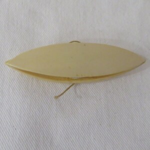 Peut inclure: Une bobine à fil en plastique blanc, d'environ la taille d'une pièce d'un euro, avec un petit trou à une extrémité pour enfiler le fil.