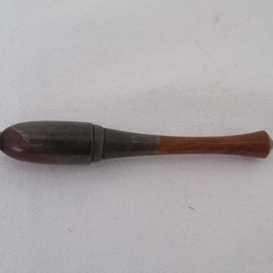 Peut inclure: Un porte-cigarette en bois et métal avec un embout en bois brun et une partie centrale en métal argenté.