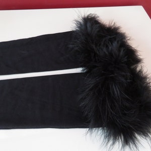 May include: Black fabric leg warmers with a black feather trim.