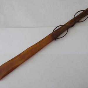 Peut inclure: Un long chausse-pied en corne brun avec une boucle en métal à l'extrémité.