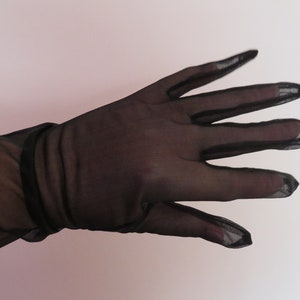 Peut inclure: Une paire de longs gants en dentelle noire avec une texture lisse.