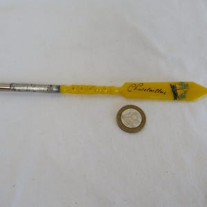 Abrecartas/pluma de inmersión vintage de plástico rígido amarillo. Recuerdo de Chatelaillon, Francia, con barco de vela. Década de 1920. Stanhope desaparecido.