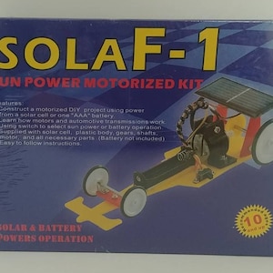 May include: A blue box with the text "SOLAF-1 SUN POWER MOTORIZED KIT" on the front. The box shows a yellow toy car with a solar panel on top. The car has black wheels and a black motor. The box also includes the text "Features:" and a list of features. The box is recommended for ages 10 and up.