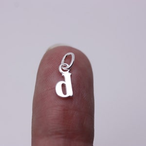May include: Silver charm in the shape of the letter 'D'.