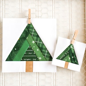 May include: Two handmade Christmas tree ornaments made from fabric scraps in shades of green. The ornaments are attached to white cardstock with wooden clothespins. The larger ornament has the text "a bright joy" printed on it.