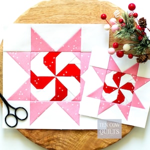 May include: Two square quilt blocks featuring a central red and white pinwheel design surrounded by pink and white star points. The blocks are made of fabric with white speckles. The text TEN COW QUILTS is visible in the bottom right corner.