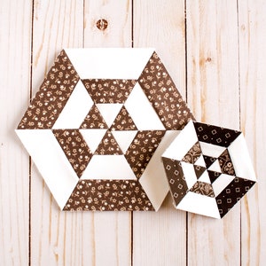 Könnte beinhalten: Zwei sechseckige Quiltblöcke aus braunem und weißem Stoff mit geometrischem Muster. Der größere Block hat einen Blumendruck auf dem braunen Stoff. Der kleinere Block hat einen einfarbigen braunen Stoff.