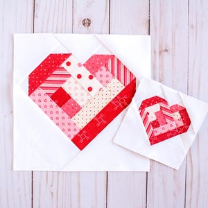 May include: Two white fabric squares with red, pink, and white patterned hearts sewn in the center. The larger heart is about 6 inches wide and the smaller heart is about 3 inches wide.
