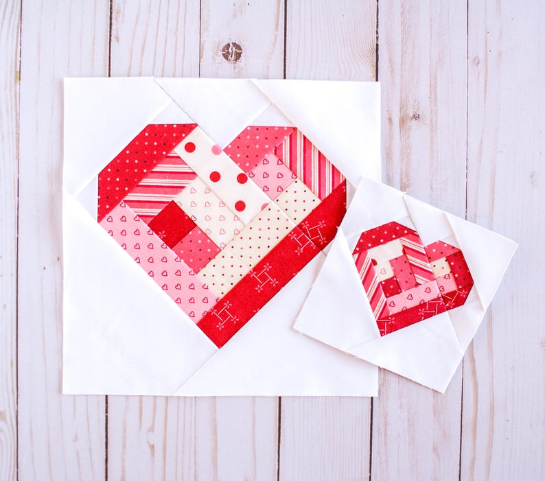 May include: Two white fabric squares with red, pink, and white patterned hearts sewn in the center. The larger heart is about 6 inches wide and the smaller heart is about 3 inches wide.