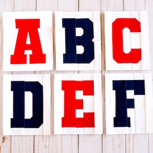 May include: Six fabric squares with the letters A, B, C, D, E, and F in red and blue. The letters are made of fabric strips sewn together.