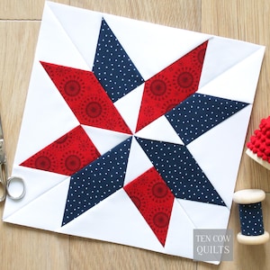 Puede incluir: Un bloque de edredón cuadrado con un diseño de estrella en rojo, blanco y azul marino. Las puntas de la estrella alternan entre tela roja estampada y tela azul marino con lunares blancos. El texto "TEN COW QUILTS" es visible.