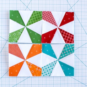 May include: Four fabric squares with a pinwheel design. The squares are made of white fabric with green, red, orange, and turquoise fabric triangles. The triangles are arranged in a pinwheel pattern.