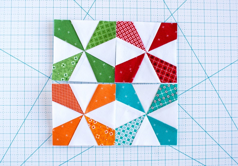 May include: Four fabric squares with a pinwheel design. The squares are made of white fabric with green, red, orange, and turquoise fabric triangles. The triangles are arranged in a pinwheel pattern.