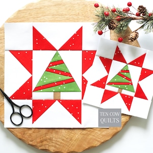Peut inclure: Deux blocs de courtepointe carrés présentant un sapin de Noël vert central avec des accents de ruban rouge sur fond blanc, entouré de pointes d'étoiles rouges à pois blancs. Une paire de ciseaux noirs est placée sur le côté gauche des blocs.