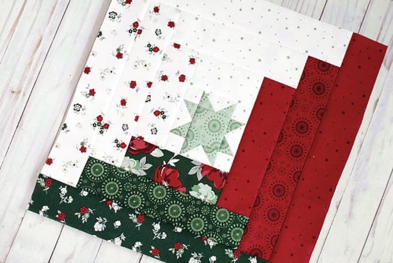 May include: A red, green and white patchwork quilt block with a star in the centre. The block is made up of different fabrics with various patterns, including floral, polka dot and geometric designs.