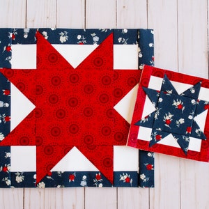 May include: Two star-shaped quilt blocks. The larger block features a red star with a circular pattern, white points, and a navy blue floral border. The smaller block has a navy blue floral star with a red border.