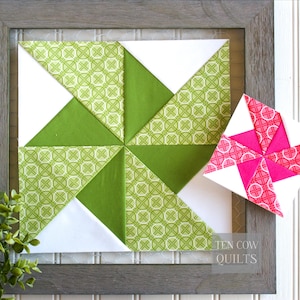 Pode incluir: Um bloco de colcha emoldurado com um design de cata-vento. O bloco apresenta tri&acirc;ngulos verdes e brancos, com um tecido verde estampado. Um cata-vento menor, separado, em rosa e branco fica ao lado. A moldura &eacute; cinza.