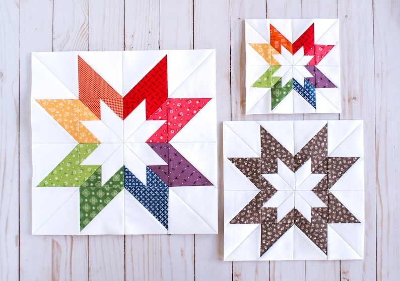 May include: Three quilt blocks featuring a star design. The largest block has a white background with a star made of eight colourful triangles. The medium block has a white background with a star made of eight brown triangles. The smallest block has a white background with a star made of eight rainbow coloured triangles.