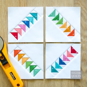 May include: Four square quilt blocks featuring white fabric with diagonal rows of colorful triangles in a rainbow gradient, each marked with a small white plus sign. A yellow rotary cutter is positioned on the left, and the text Ten Cow Quilts is visible in the bottom right corner.