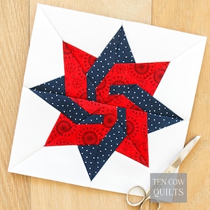 May include: A square quilt block featuring a star design in red and navy blue fabrics, set against a white background. The red fabric has a circular pattern, while the navy has white polka dots. The scissors are on the right side of the quilt block. The text "TEN COW QUILTS" is in the bottom right corner.