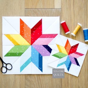 Puede incluir: Dos bloques de edredón cuadrados con un patrón de estrella multicolor y detalles en tela blanca. Las puntas de la estrella están hechas de tela en tonos rojo, naranja, amarillo, verde, azul y morado con motas blancas. Incluye carretes de hilo rojo, amarillo y azul y tijeras negras.
