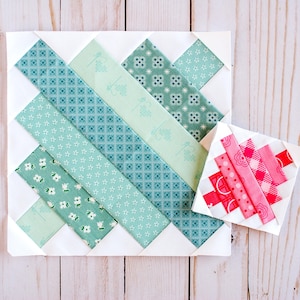 May include: Two quilt blocks, one large and one small, on a light wood surface. The larger block features diagonal strips of teal and green patterned fabric. The smaller block has pink and red strips. Both are set on white backgrounds.