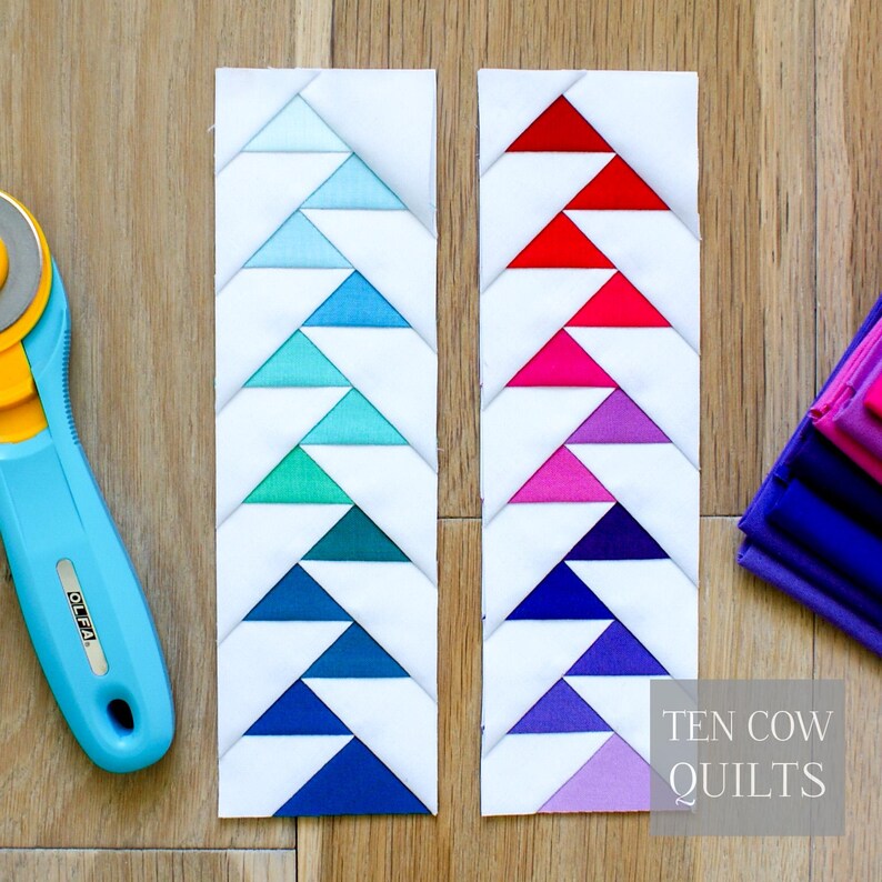 Puede incluir: Dos piezas rectangulares de tela con fondos blancos y patrones triangulares coloridos. Una pieza tiene tri&aacute;ngulos azules a verdes, la otra rojos a morados. Tambi&eacute;n se ven un cortador rotatorio azul y retales de tela. El texto "TEN COW QUILTS" est&aacute; en la imagen.