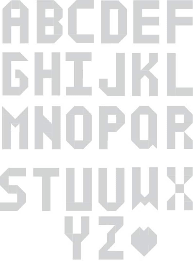 May include: A gray alphabet font with blocky, geometric letters. The letters are in uppercase and are arranged in three rows. The letters are all the same size and are evenly spaced.
