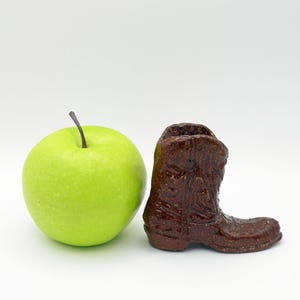 May include: A green apple and a brown ceramic cowboy boot.