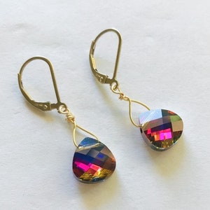 May include: A pair of gold dangle earrings with teardrop-shaped iridescent crystals. The crystals have a multi-colored effect, with shades of red, purple, and blue.