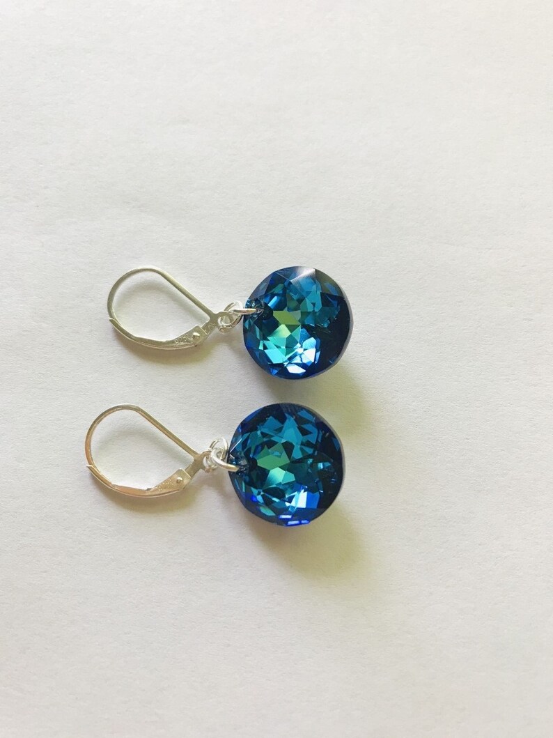 May include: A pair of silver earrings with blue crystal teardrop-shaped stones.