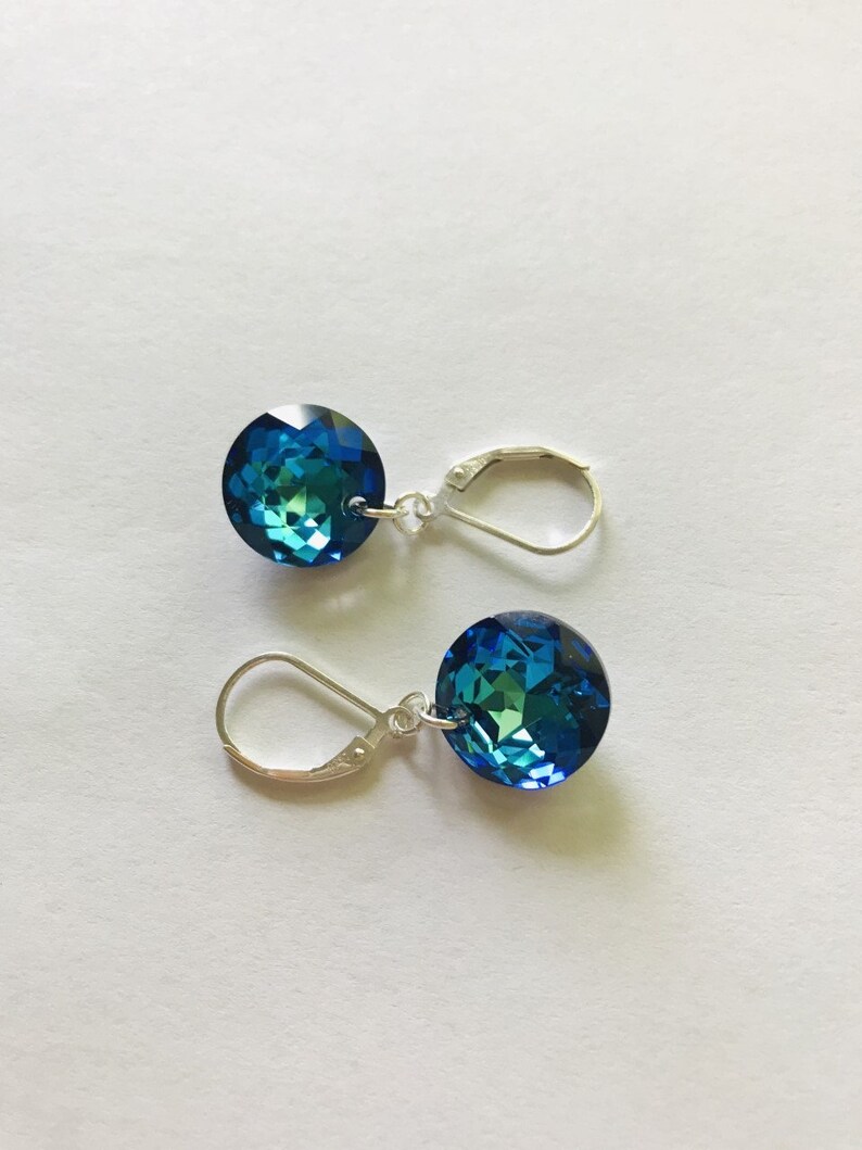 May include: A pair of silver dangle earrings with round blue crystal stones.