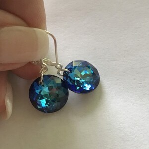 May include: A pair of silver dangle earrings with blue crystal stones. The stones are faceted and have a shimmery finish.