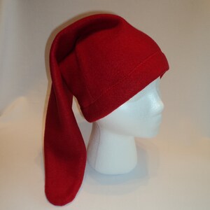May include: A red fleece hat with a long, pointed tail. The hat is worn on a white mannequin head.