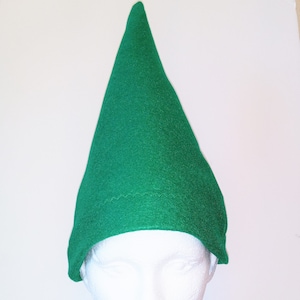 May include: A green felt elf hat with a pointed tip. The hat is on a white mannequin head.