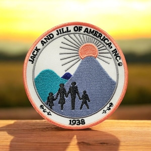 May include: Embroidered patch with the text "JACK AND JILL OF AMERICA, INC." encircling a mountain scene with a family silhouette. The patch features a sun, mountains, and the year "1938". The patch has a white background with a peach border.