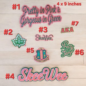 May include: Seven iron-on patches with pink and green colors. The patches feature various designs, including text, Greek letters, and a crest. The patches are arranged in a circle on a wooden surface. The text on the patches includes "Pretty in Pink & Gorgeous in Green", "Skee Wee", "AKA", and "Pretty Girl".