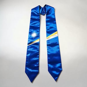 May include: A royal blue satin graduation stole featuring the flag design of the Marshall Islands. The stole displays a white star with radiating points above two diagonal stripes in orange and white, set against a solid blue fabric background.