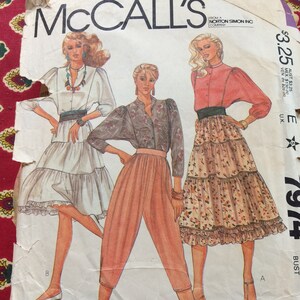 May include: Vintage McCall's sewing pattern featuring illustrations of three women in 1980s fashion. The pattern includes designs for a tiered skirt, high-waisted pants, and a button-down shirt. The pattern is labeled "Carole Little."