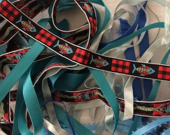 May include: A collection of colorful ribbons in various shades of blue and teal. Some ribbons have a fish pattern on a black and red plaid background. The ribbons are arranged in a tangled pile.