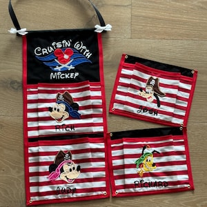 May include: A red and white striped fabric organizer with black pockets and a black strap. The organizer has four pockets with embroidered Disney characters, including Mickey Mouse, Goofy, and Pluto. The top pocket has the text "Cruisin' With Mickey" embroidered on it. The other pockets have the names "Rich", "Judy", "Josh", and "Richard" embroidered on them.